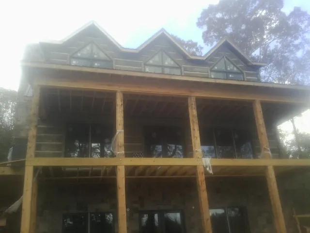 Dormers and porch framing on a large log home under construction — Roof Coating work by our crew in Averill Park