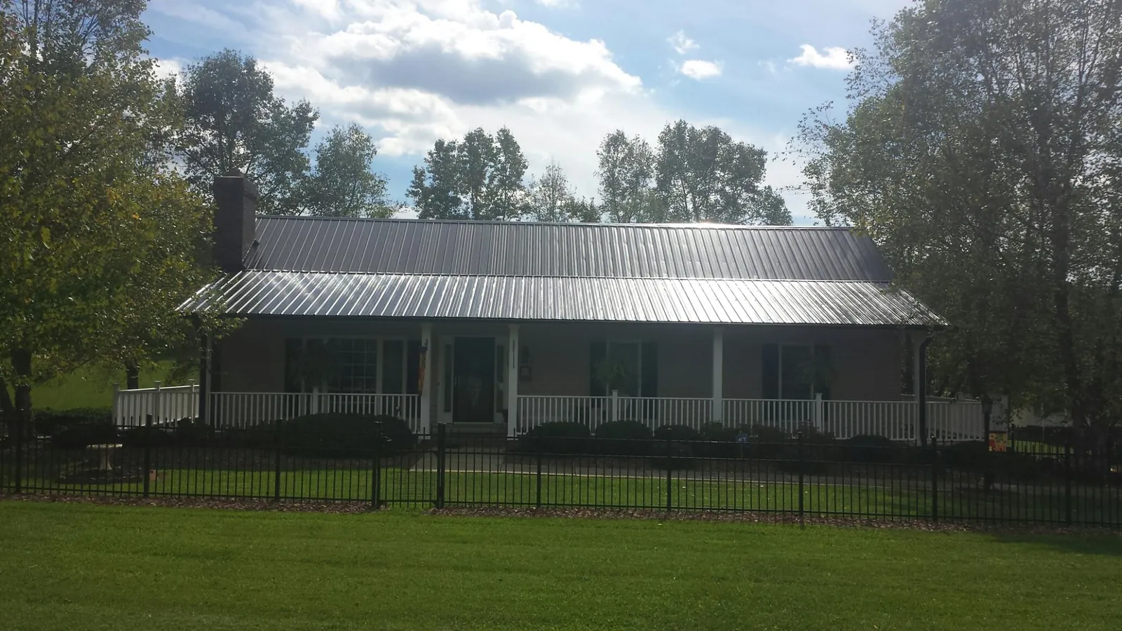 Gray metal roof on a brick ranch with a full width front porch — Gutter Guard Installation work by our crew in Averill Park
