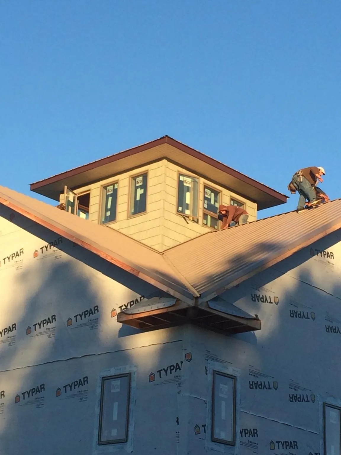 Roofers working around a rooftop cupola on a new metal roof at sunset — Roof Waterproofing in Averill Park by Roofing Brothers